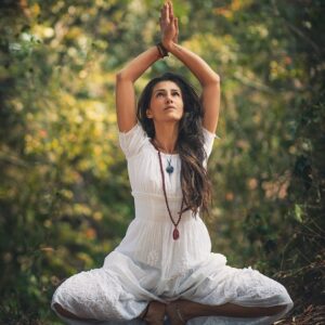 A woman meditating outdoors in a forest setting, embracing tranquility.