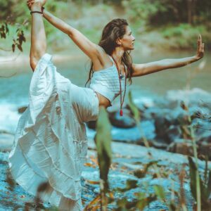 A serene scene of a woman practicing yoga by a picturesque river shore, embodying balance and tranquility.